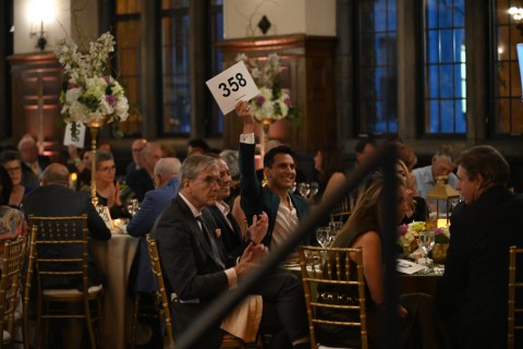 A male guest of the Annual Trustee Benefit Gala holds up a numbered paddle during the auction event.
