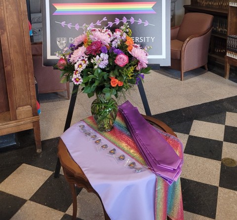 Table with floral bouquet, rainbow colors and lavender stoles