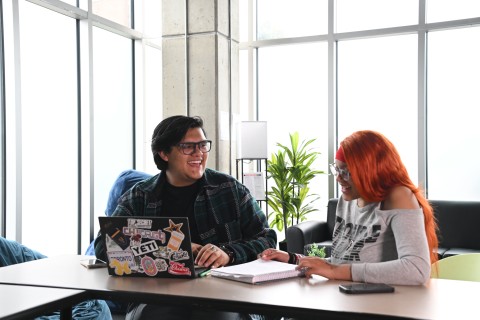 Two students takling at a table