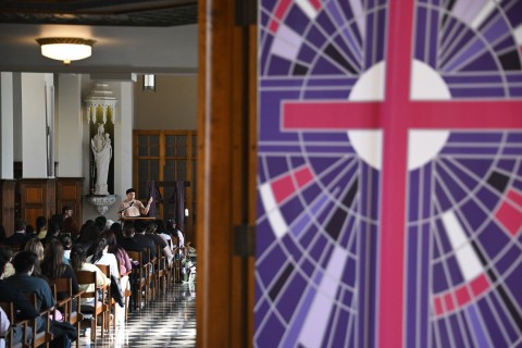 Students at worship in chapel with stained glass