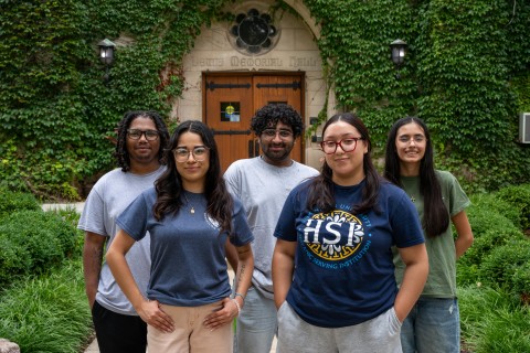 Five students standing in front of campus building