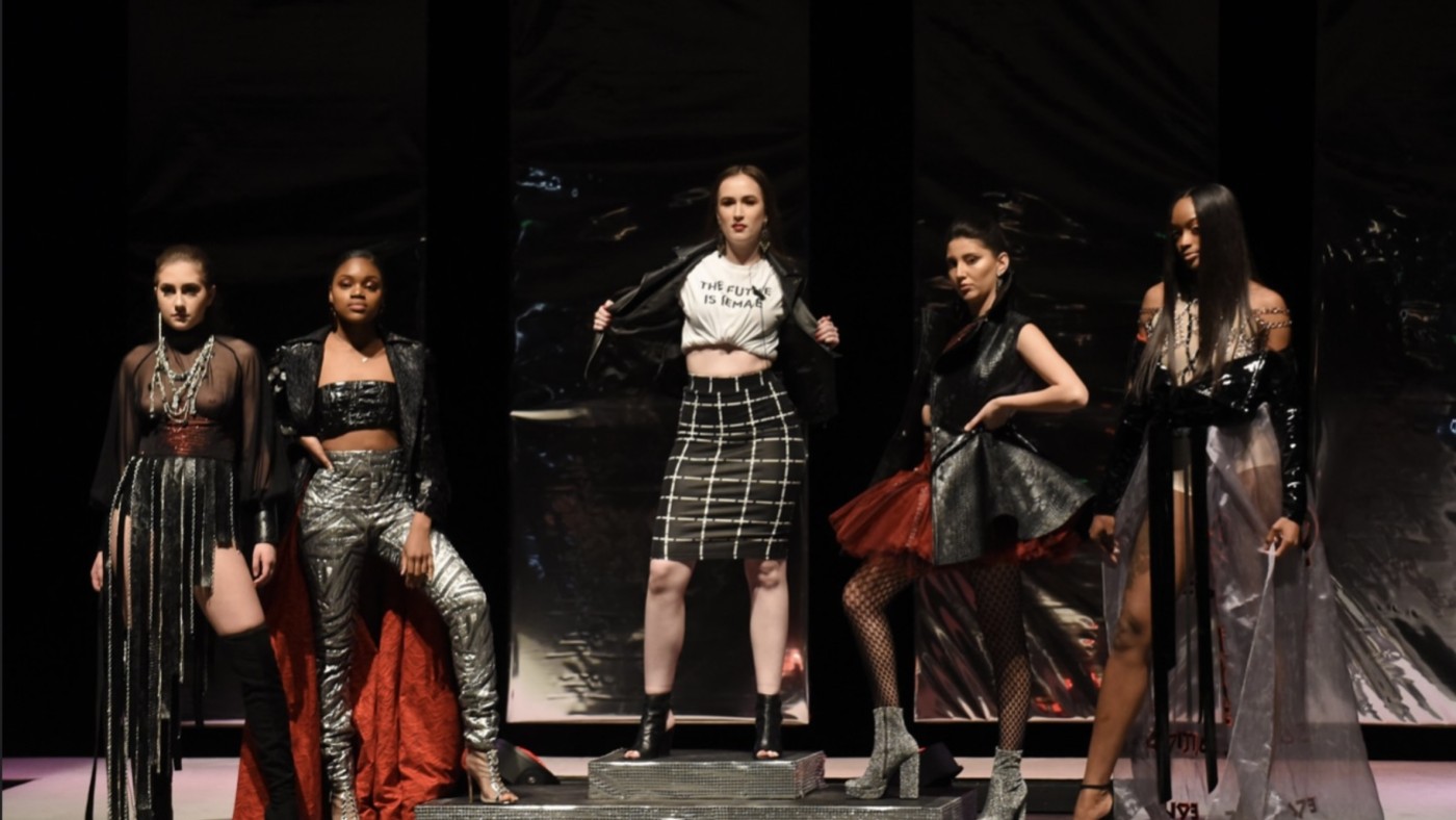 Models on stage wearing outfits designed by students at Dominican University's Annual Fashion Show