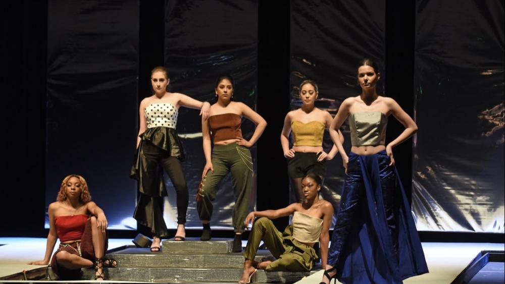 Models on stage wearing outfits designed by students at Dominican University's Annual Fashion Show