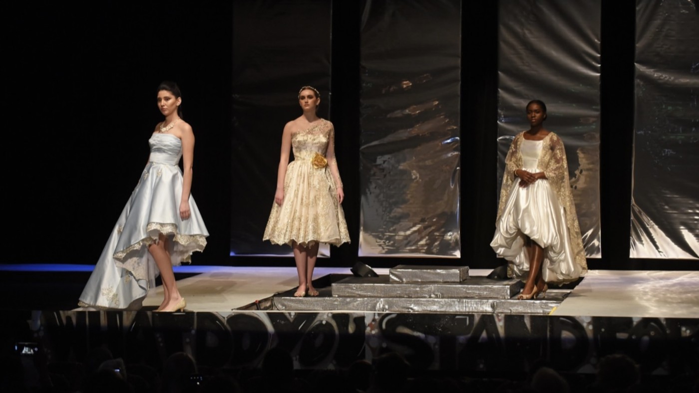 Models on stage wearing outfits designed by students at Dominican University's Annual Fashion Show