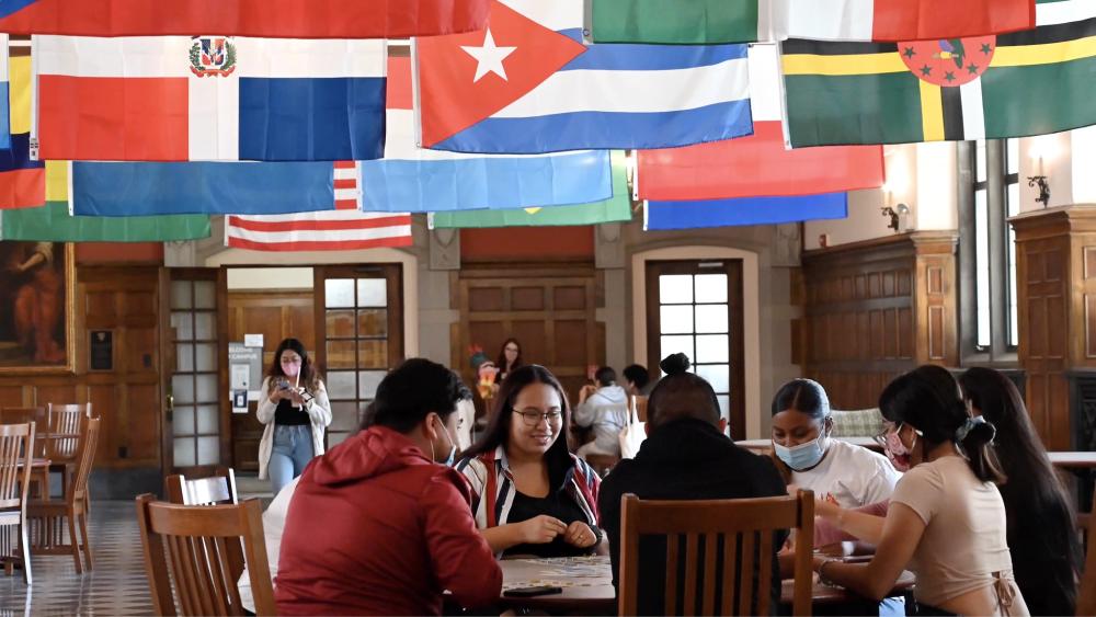 Students seated at a table under Hispanic flags