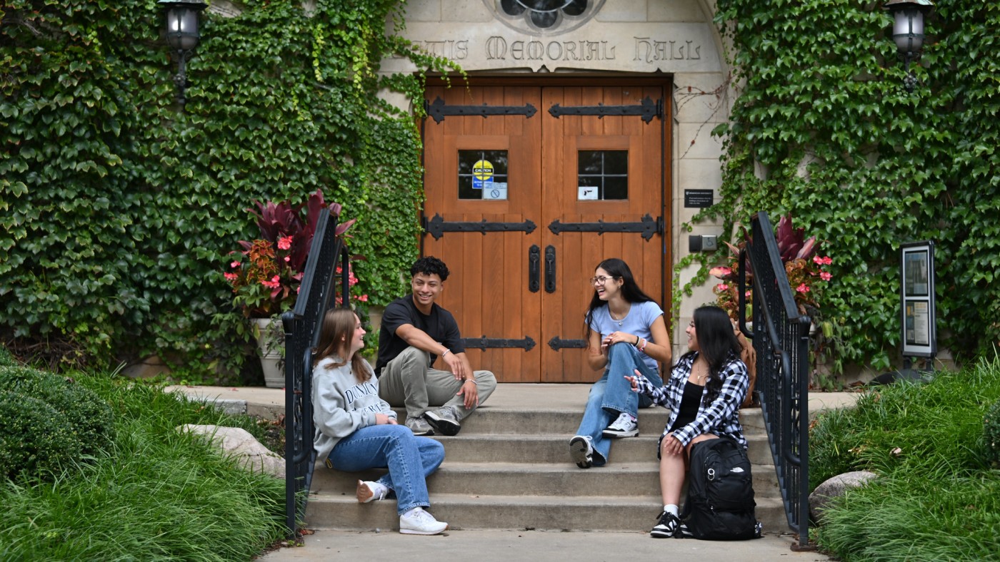 Four students seated on steps of campus building