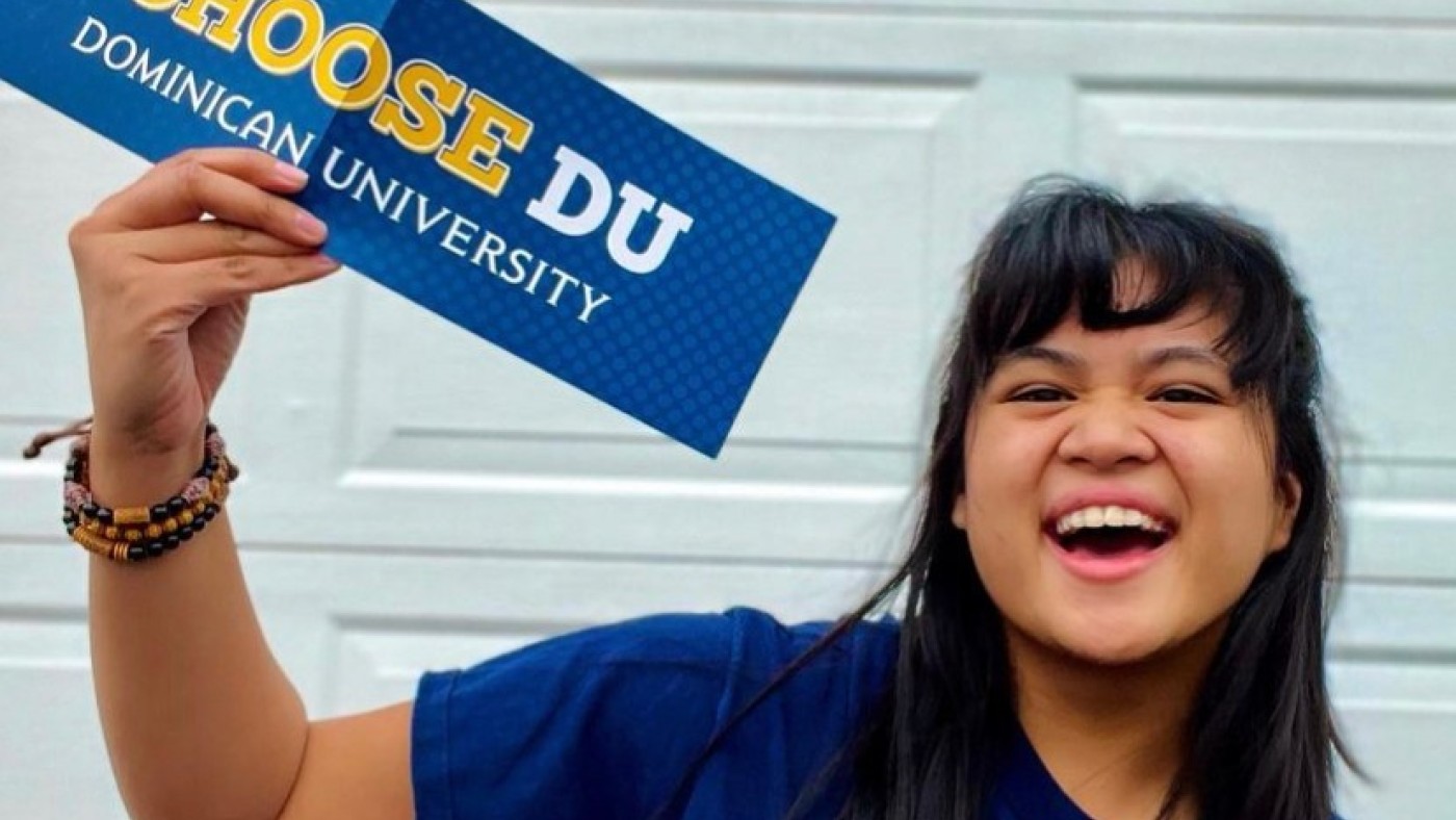 Student holding I Choose DU Placard