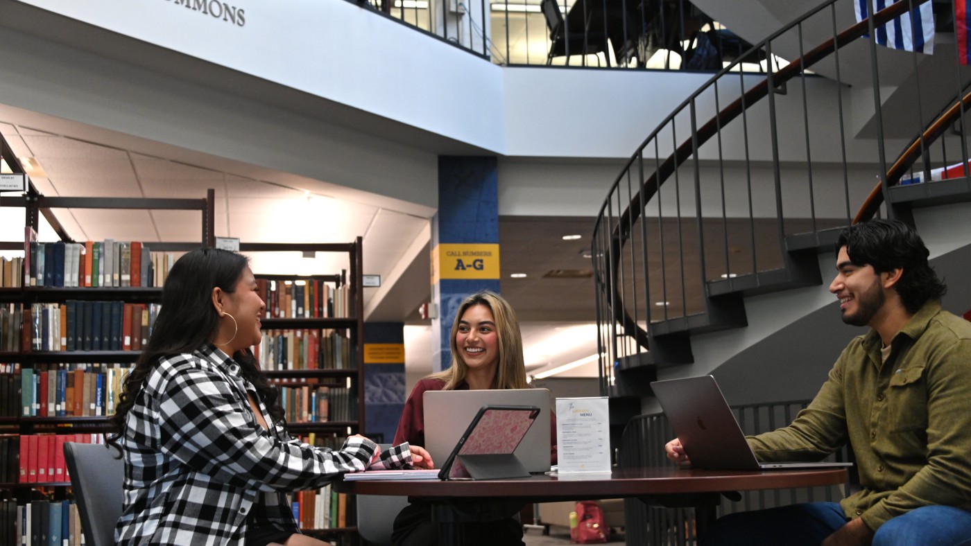 Three students seated at a table in the library