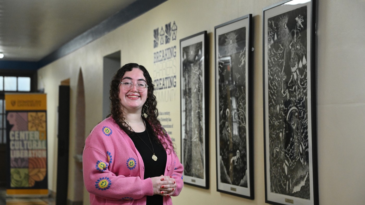 Art student Emily Reynoso Muñoz standing in front of her woodblock prints depicting Biblical themes.