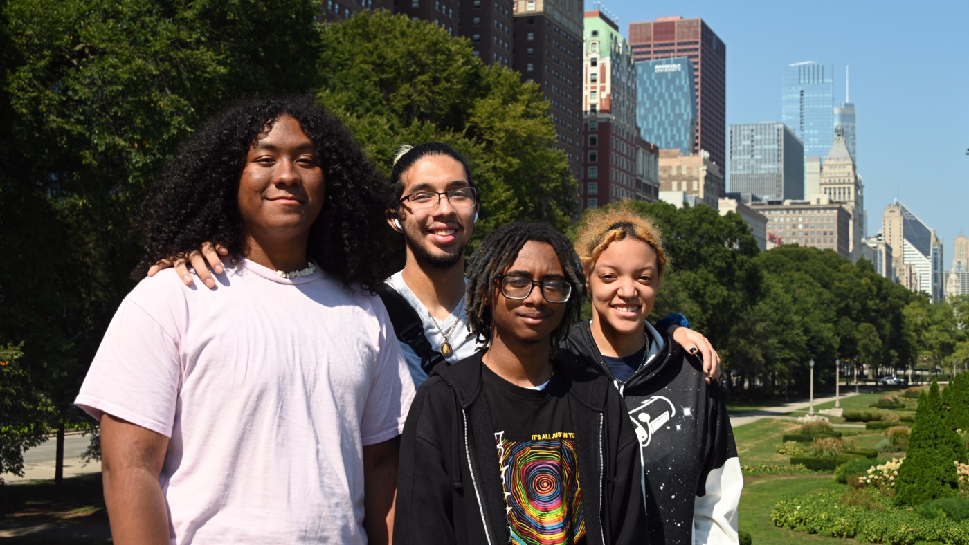 Four Dominican University students pose with the city skyline as a backdrop.