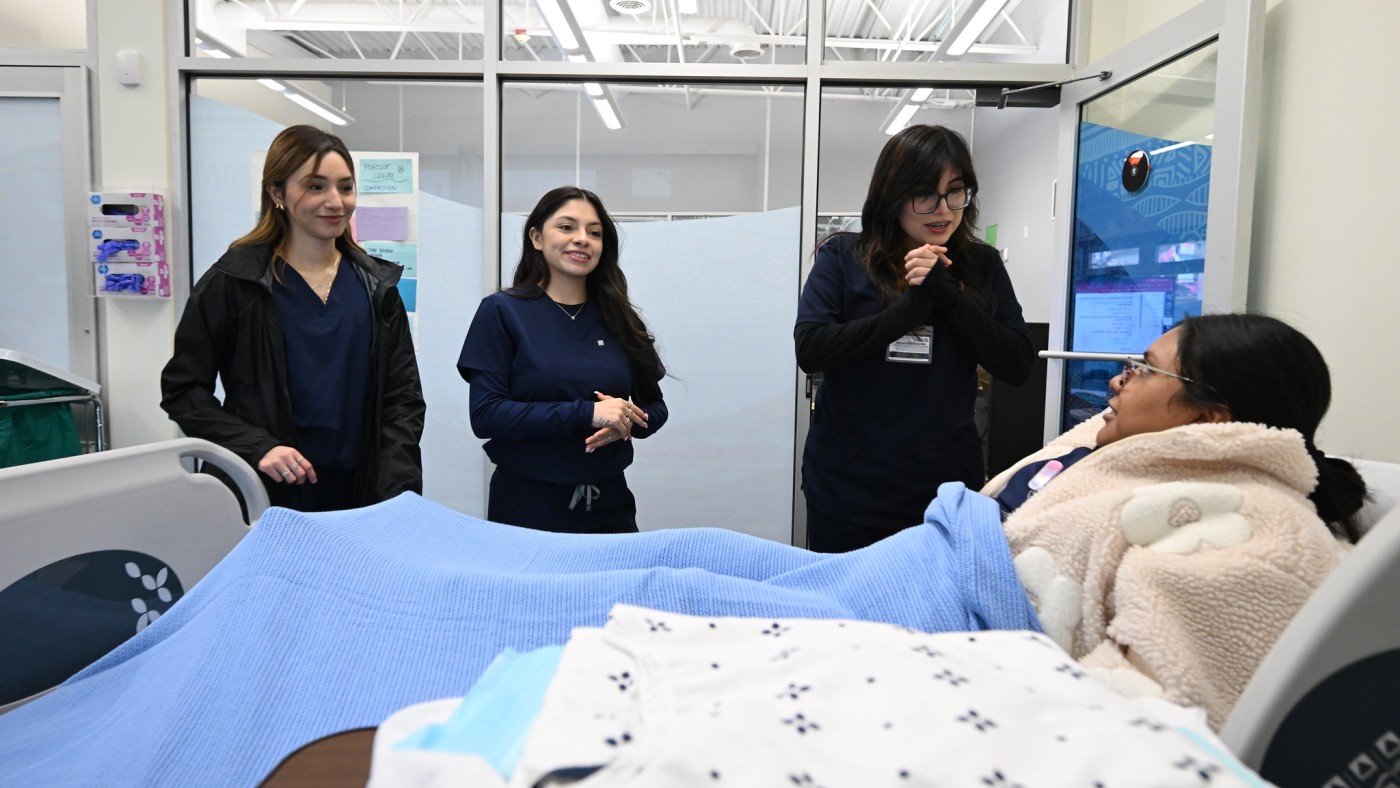 Three students observing patient in hospital bed