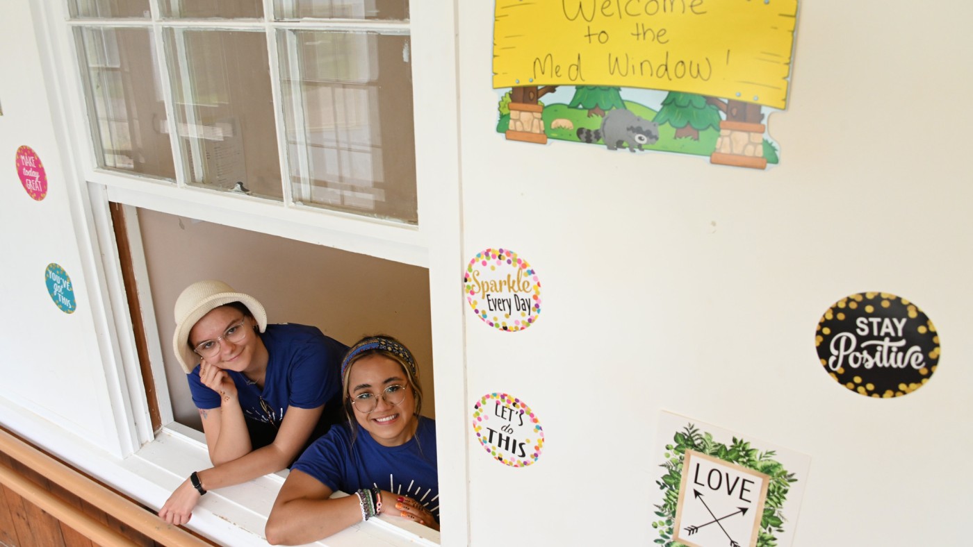 Two students looking out window, building signage
