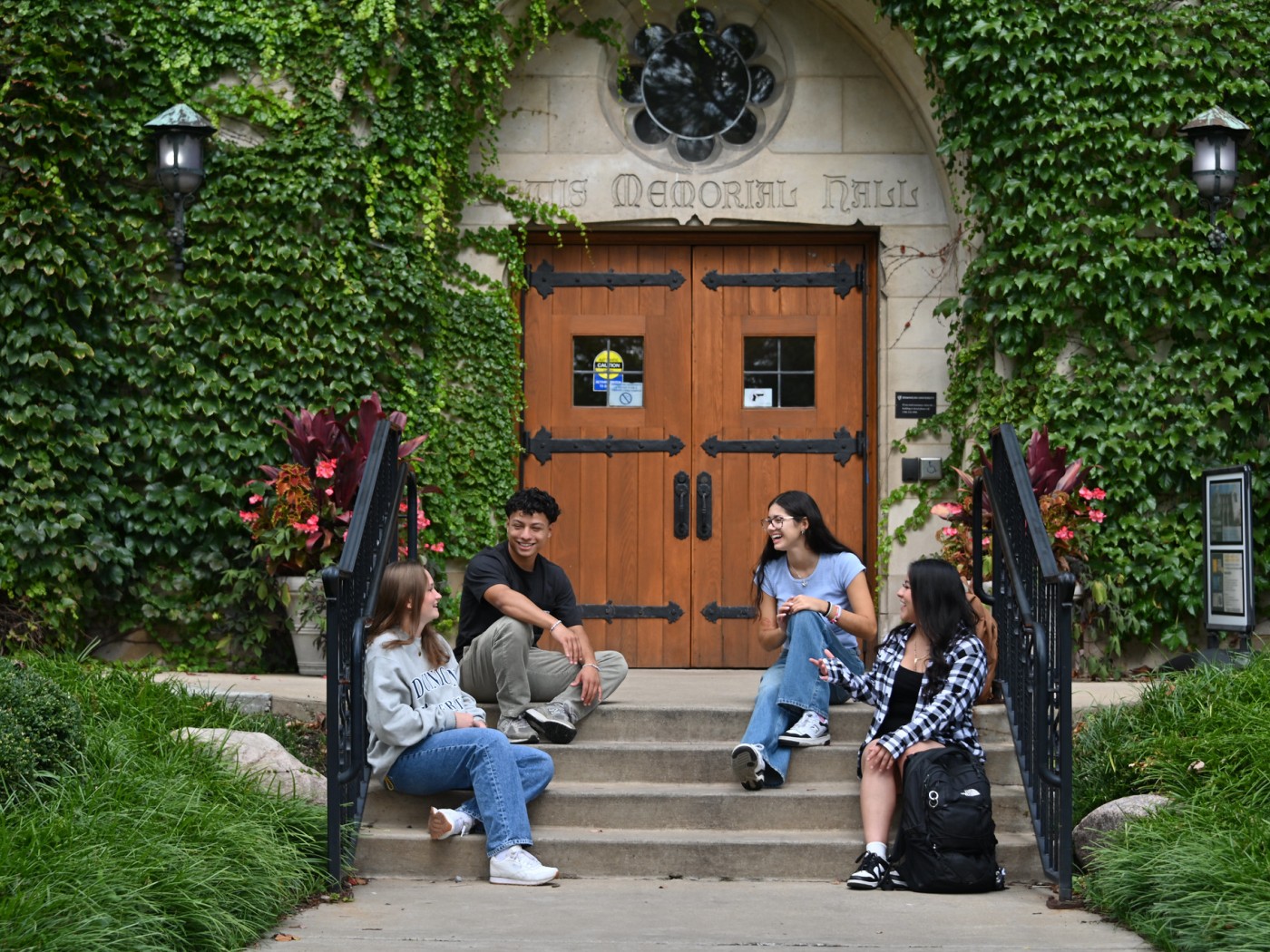 Four students seated on steps of campus building