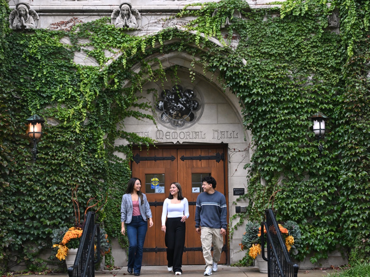 Three students walking down the stairs in front of Lewis Hall on Dominican University's main campus