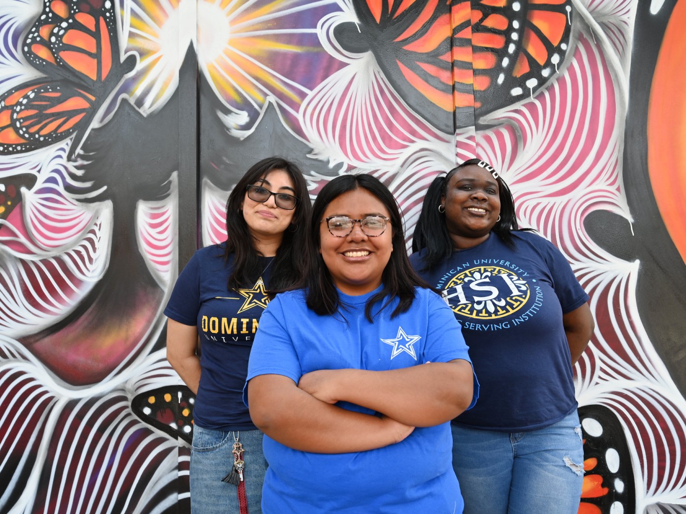 Three students in front of a mural