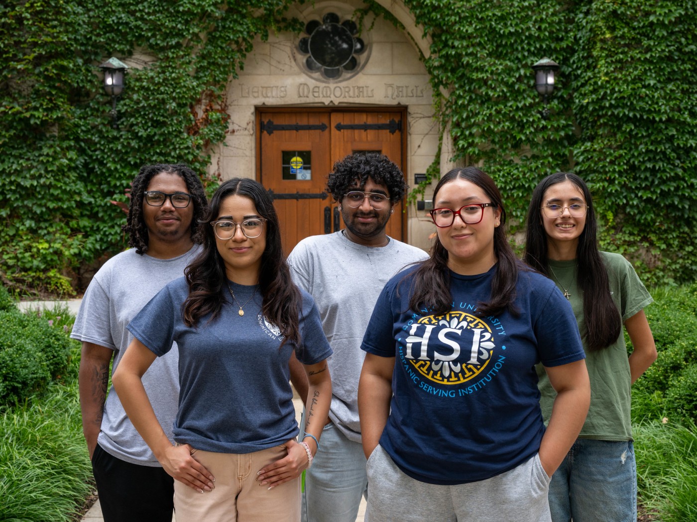 Five students standing in front of campus building